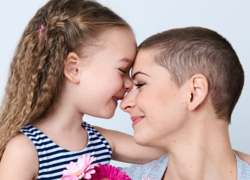 Imagem de uma menina que abraça uma mulher. Ambas estão felizes e representa o atendimento de excelência e o resultado de pesquisas e inovação na área de oncologia e hematologia do Einstein
