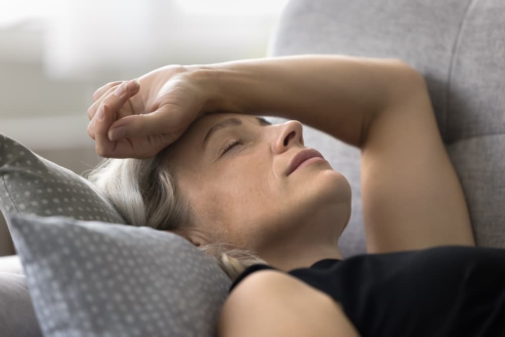 Uma mulher deitada descansando após sentir alguns sintomas do Climatério