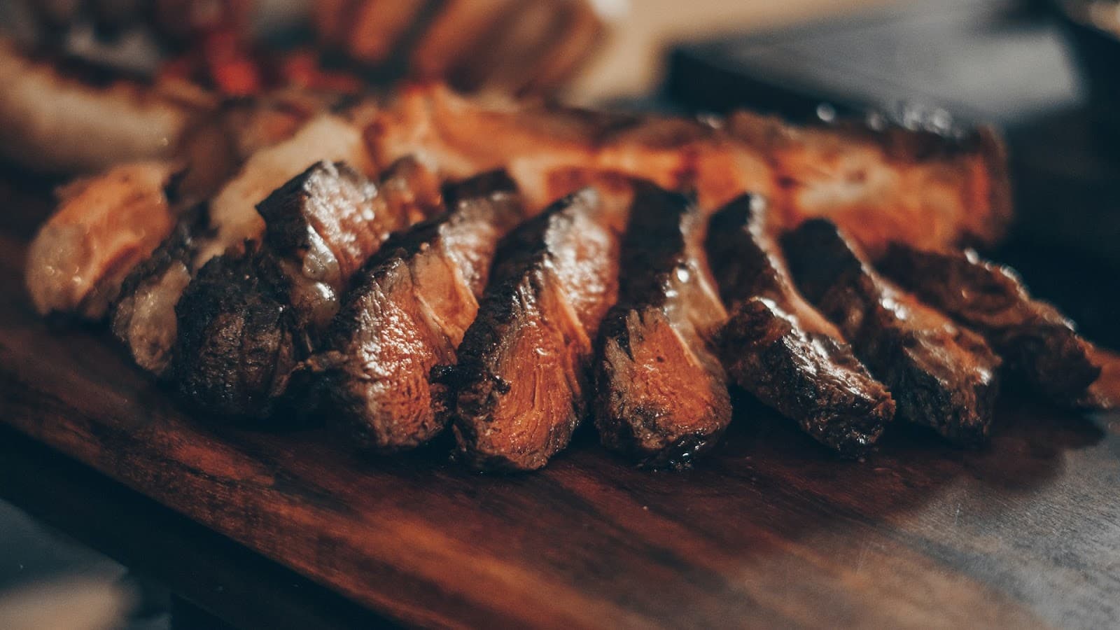 Em uma tábua de madeira, uma peça de carne cortada em tiras após ser assada em uma churrasqueira.