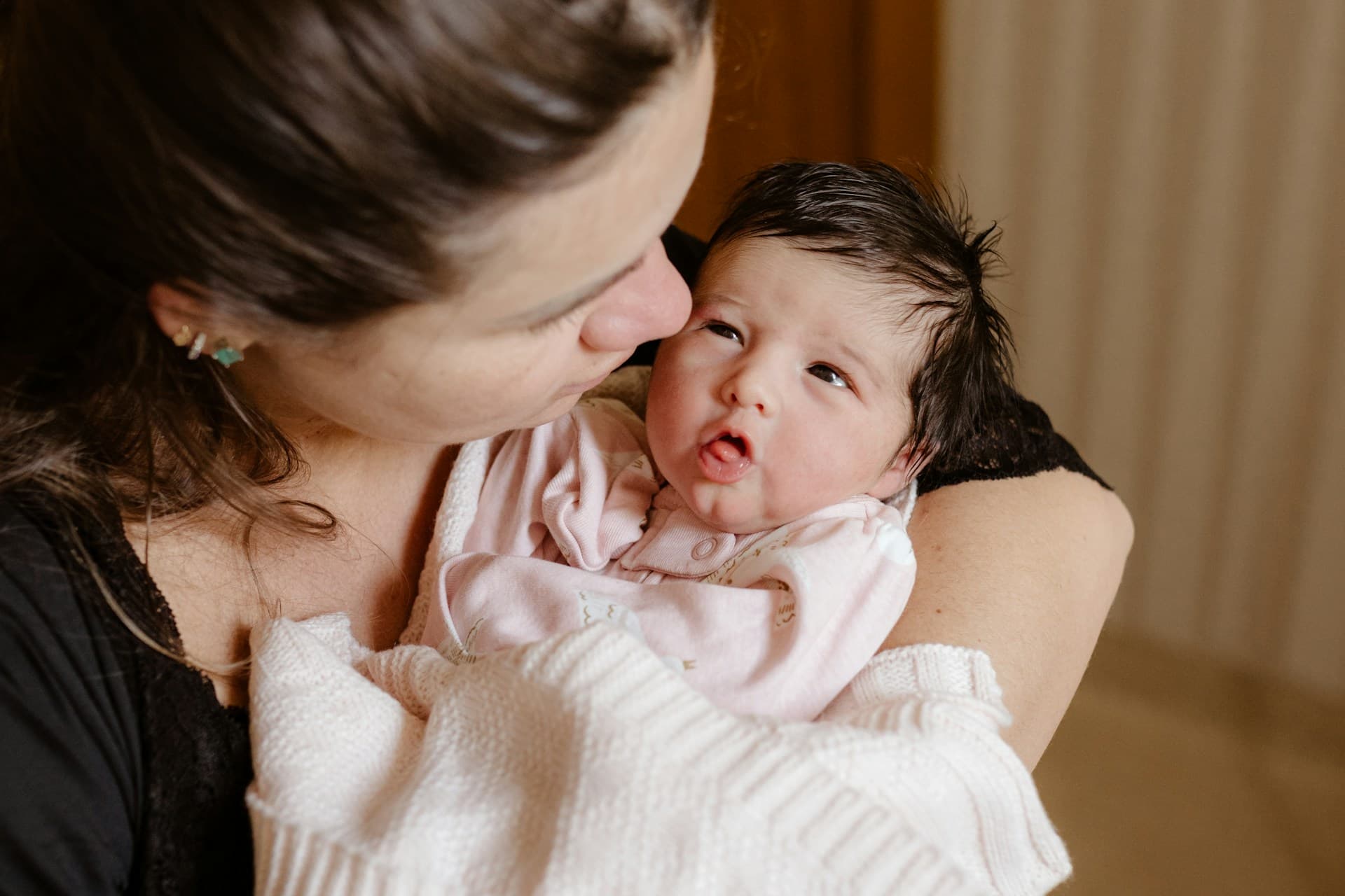 Uma mãe segurando um bebê recém-nascido no colo.