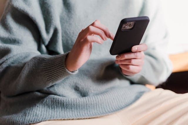 Pessoa sentada com um smartphone nas mãos