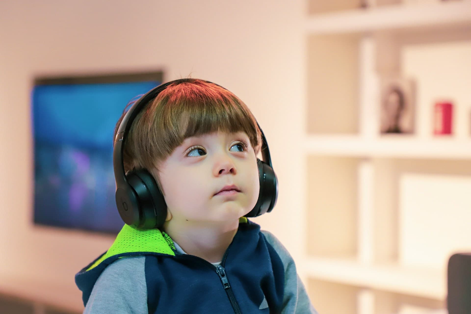 Criança neuroatípica utilizando um protetor auricular (fones de ouvidos) demonstrando calma e foco.