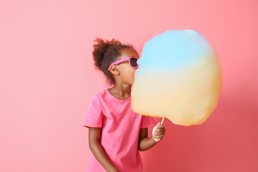 Little,African-american,Girl,Eating,Cotton,Candy,On,Color,Background