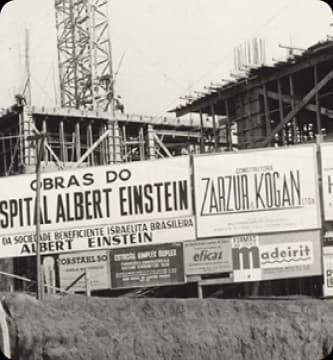 Foto histórica da construção do Einstein, mostra o prédio em estrutura inicial, representa um marco na memória institucional e o compromisso com a excelência em saúde desde o início.
