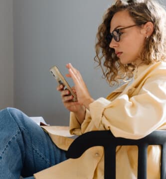 Mulher sentada em uma cadeira olhando para o celular Mulher sentada em uma cadeira olhando para o celular