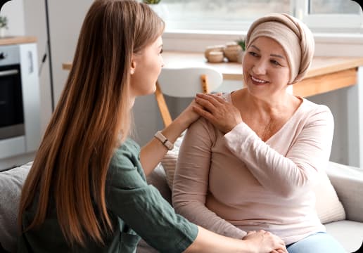 Mulher com lenço na cabeça sorrindo enquanto conversa com jovem que a conforta, simbolizando acolhimento, apoio emocional e cuidado especializado da Oncologia e Hematologia Einstein Mulher com lenço na cabeça sorrindo enquanto conversa com jovem que a conforta, simbolizando acolhimento, apoio emocional e cuidado especializado da Oncologia e Hematologia Einstein