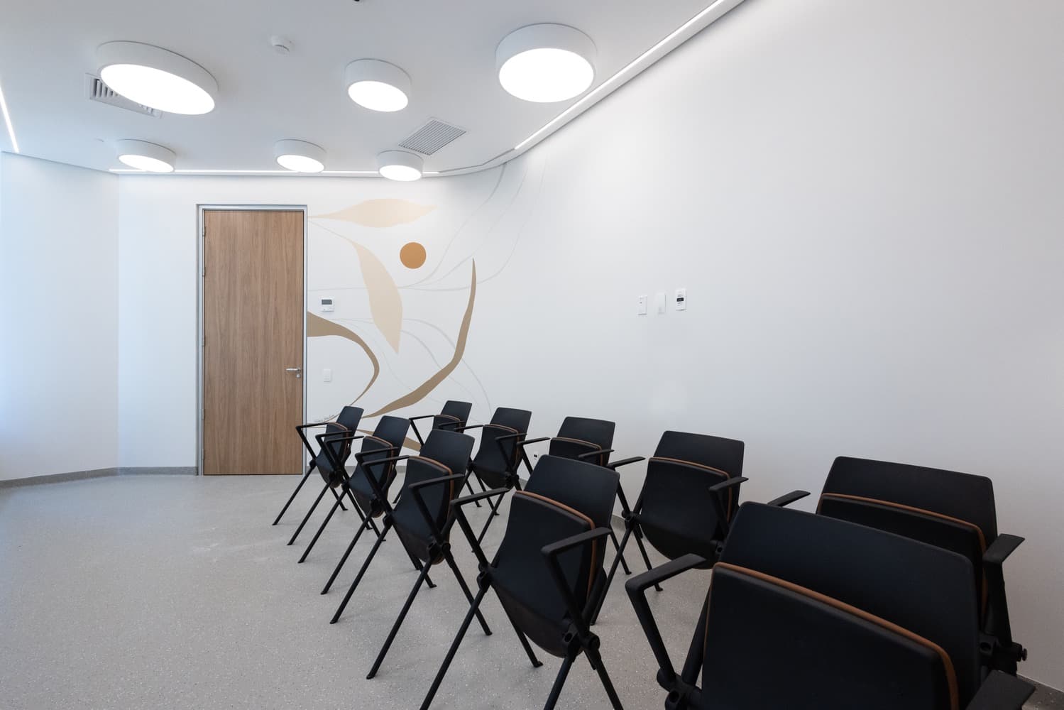 Imagem de sala para terapias. A sala é organizada com várias cadeiras dispostas em duas fileiras lado a lado. O ambiente é acolhedor e preparado para proporcionar um espaço seguro e confortável para as sessões de terapia em grupo.