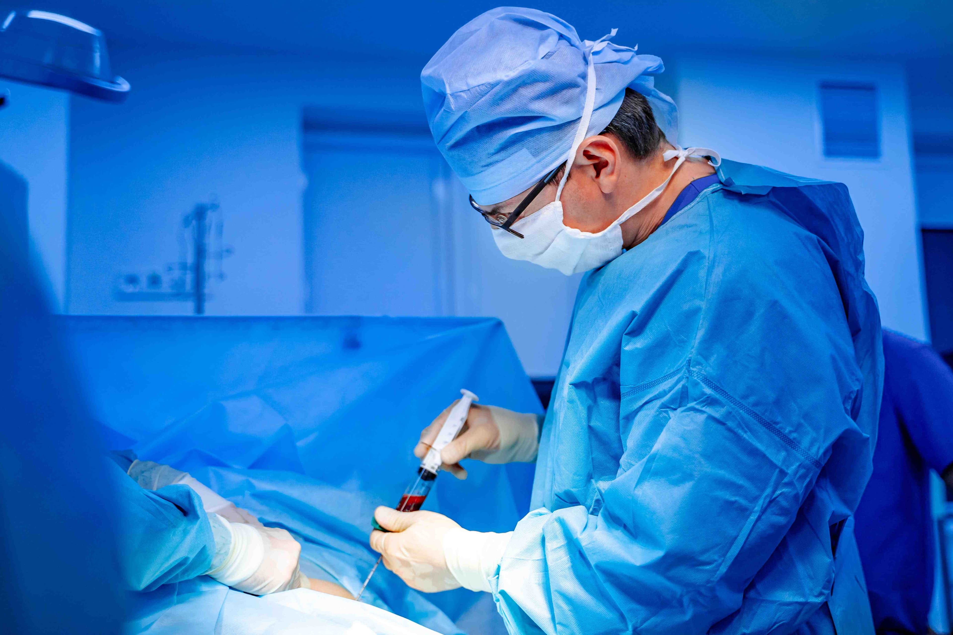 Cirurgião realiza procedimento médico de transplante de medula óssea em ambiente hospitalar esterilizado