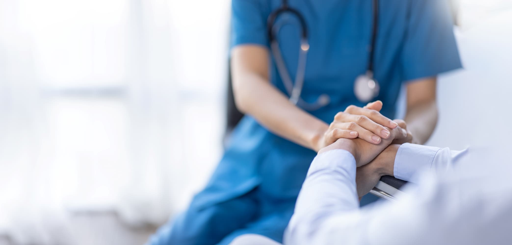 Profissional da saúde segura a mão de um paciente, representa o compromisso institucional com a qualidade, segurança e atuação no SUS, promovendo um atendimento humanizado e eficaz para todos.