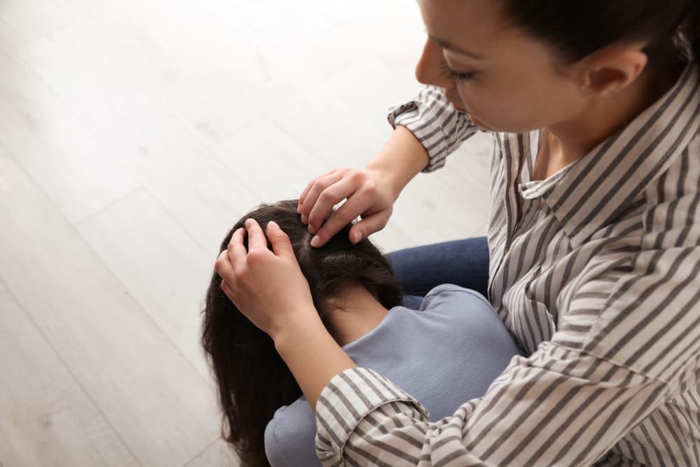 Uma pessoa verificando a existência de piolhos na cabeça de uma criança