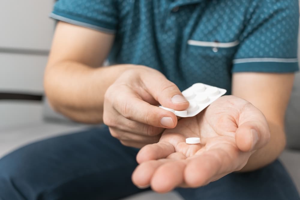 Uma pessoa destaca um comprimido de prednisolona de uma cartela para tomar.