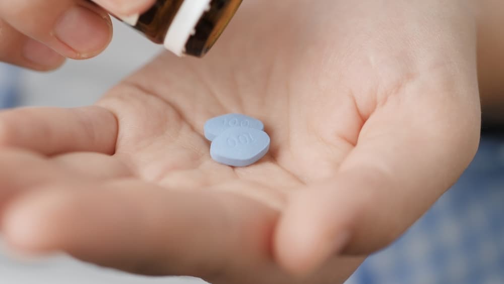 Uma pessoa com dois comprimidos de Sildenafila - princípio ativo do viagra