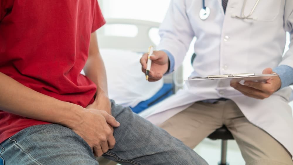 Um médico está atendendo um paciente em um ambiente hospitalar, realizando a anamnese.