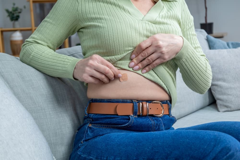 Uma pessoa aplicando adesivo hormonal na região do barriga