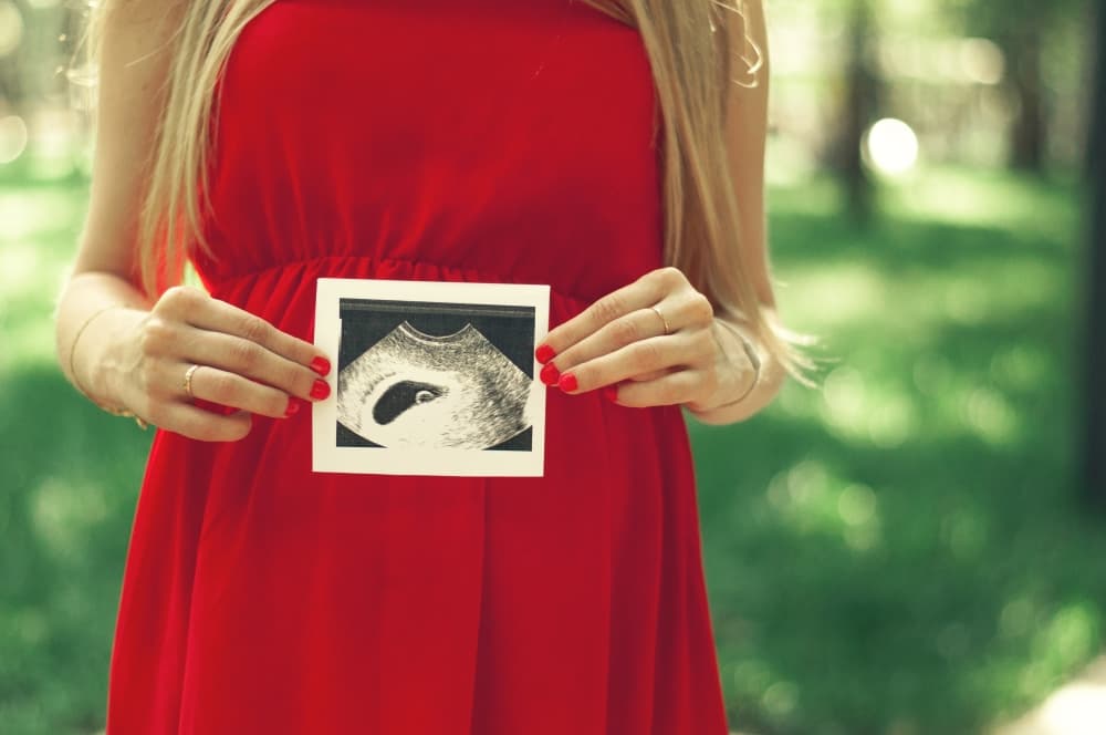 Uma pessoa grávida exibindo uma imagem de ultrassonografia - ultrassom transvaginal.