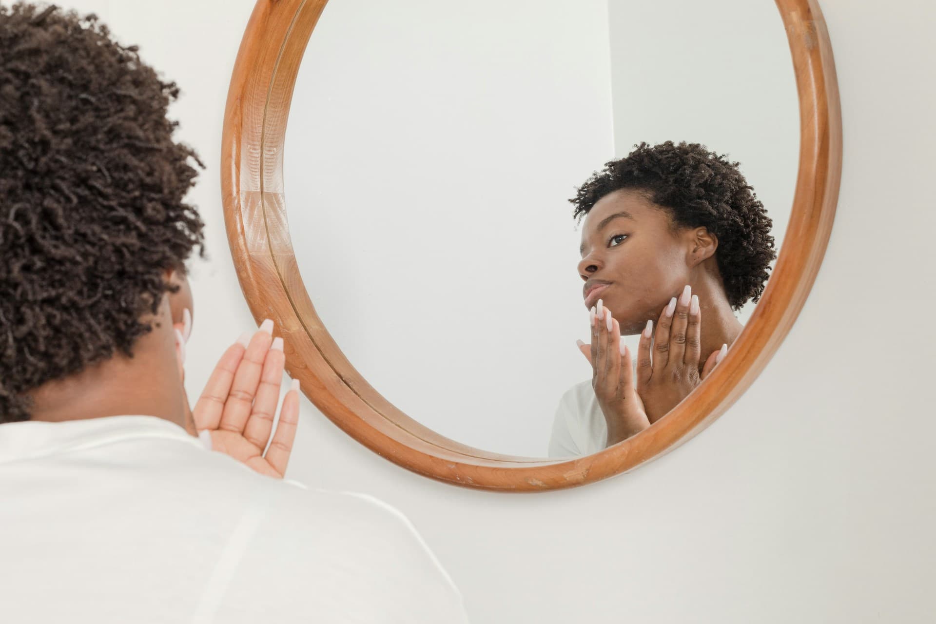Uma pessoa olhando no espelho enquanto massageia o rosto em uma sessão de skincare
