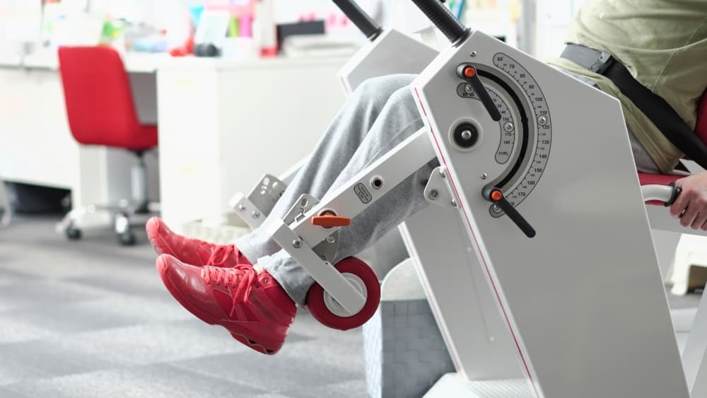 Uma pessoa em uma cadeira flexora fazendo exercício de força e resistência.