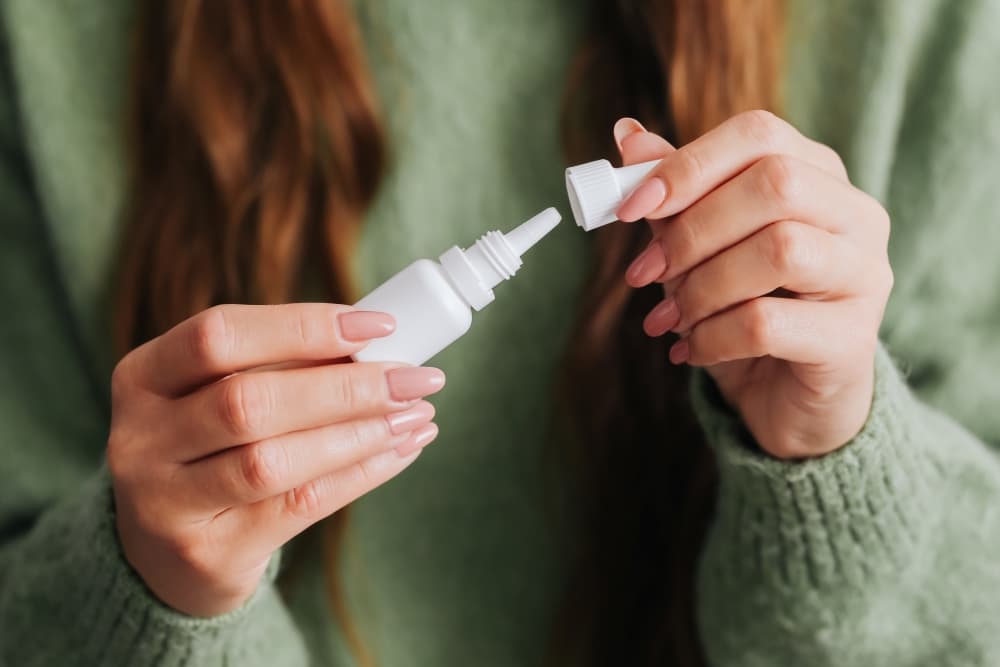 Uma pessoa com um frasco de antibiótico - colírio nas mãos