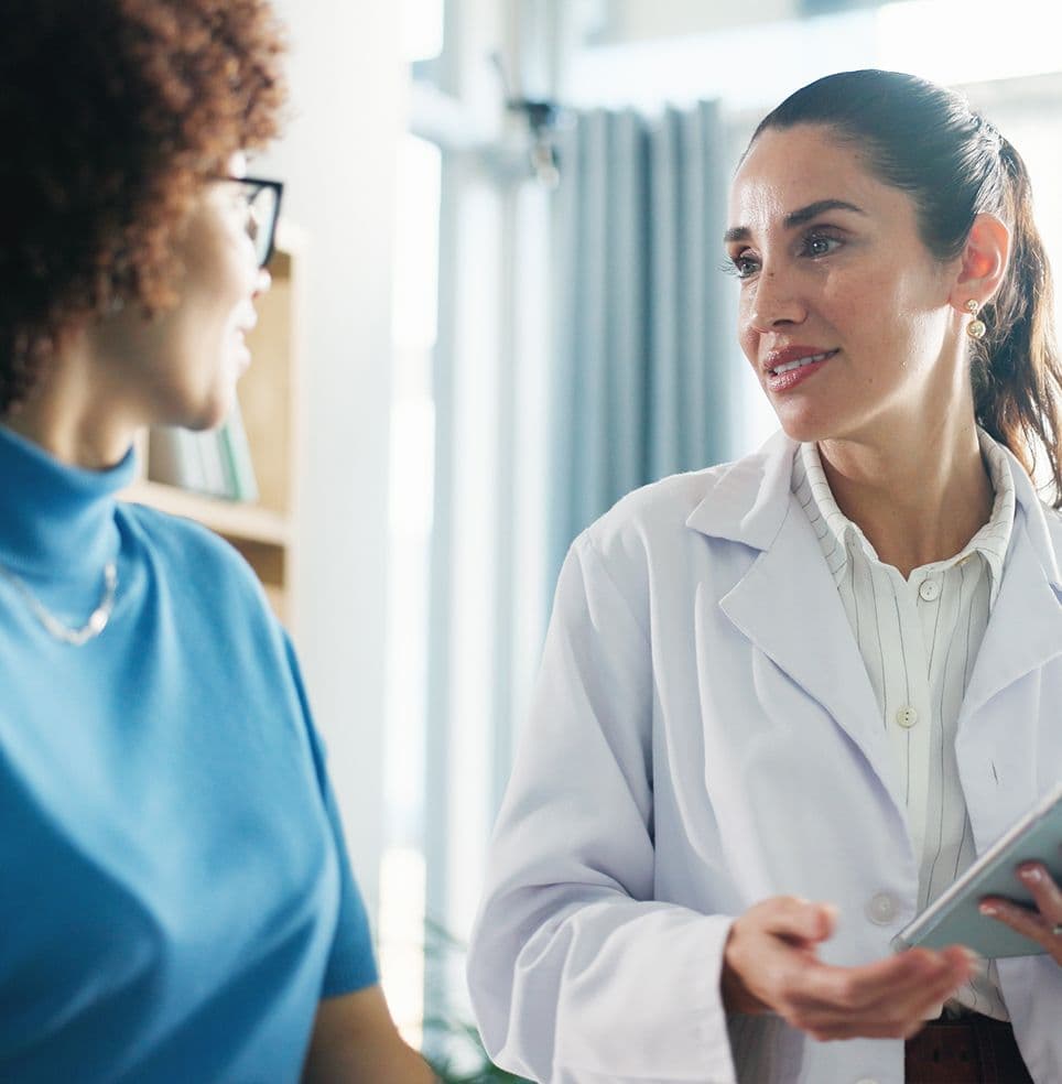 Médica conversa com paciente durante consulta, segurando uma prancheta em um ambiente claro de atendimento em saúde. Médica conversa com paciente durante consulta, segurando uma prancheta em um ambiente claro de atendimento em saúde.