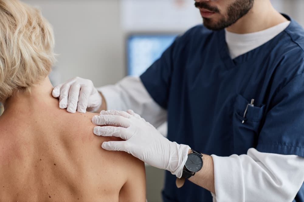Um médico examinando a pele de uma paciente que possui ferida não cicatrizada