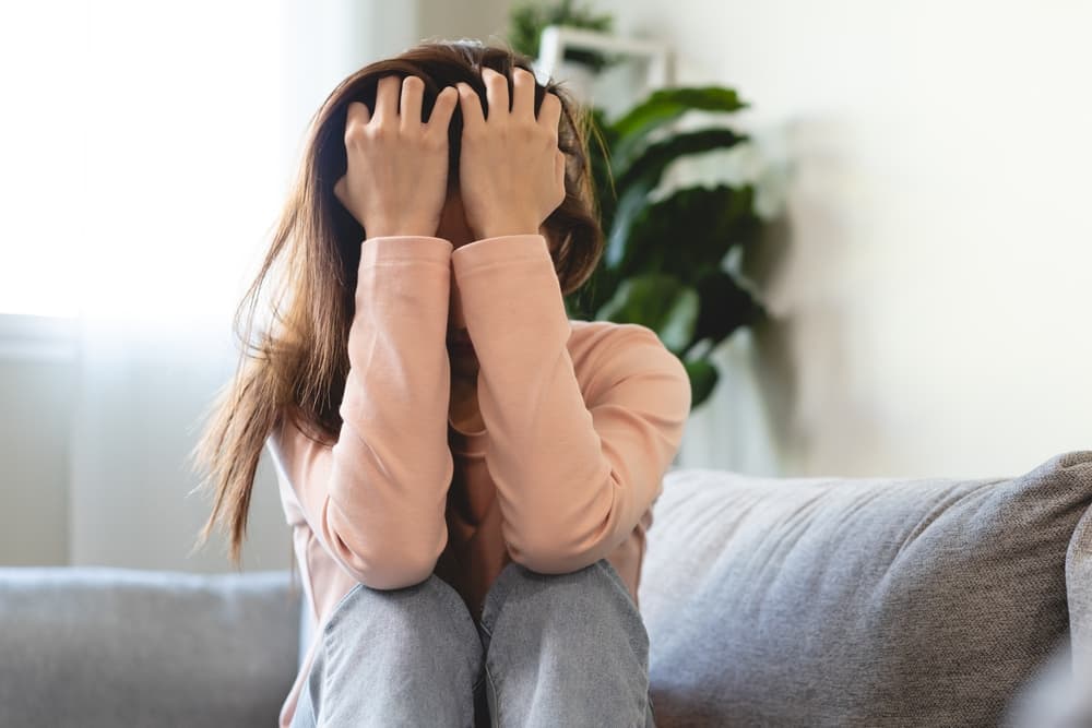 Pessoa sentada com as mãos no rosto em momento de crise.