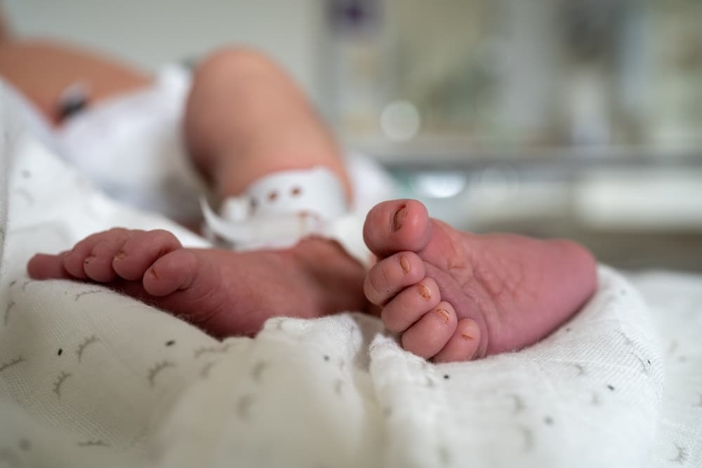 Imagem de pés de um bebê em uma cama