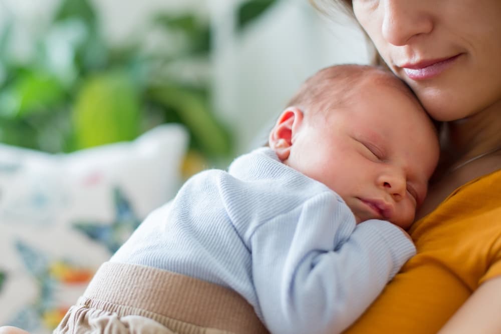 Mãe com um bebê (RN) recém nascido no colo.