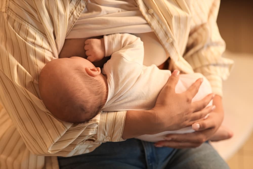 Um bebê sendo amamentado pela sua mãe com leite materno.