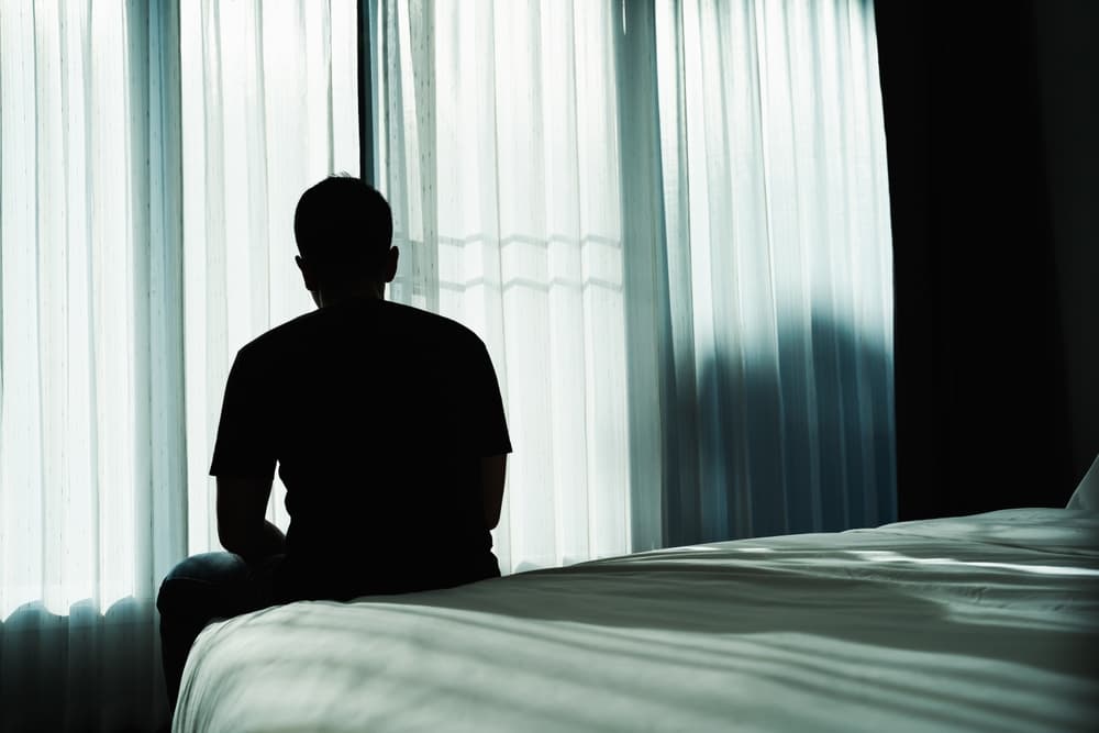 Silhouette,Depressed,Man,Sadly,Sitting,On,The,Bed,In,The