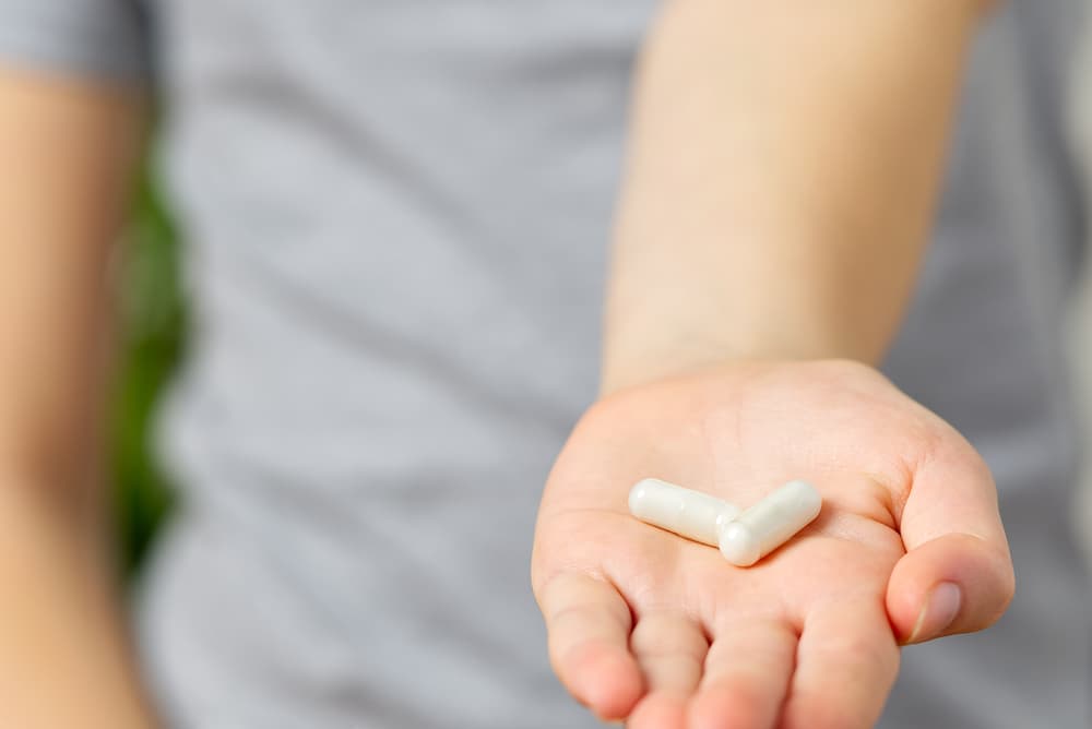 Pessoal com a mão aberta com duas cápsulas de medicamento