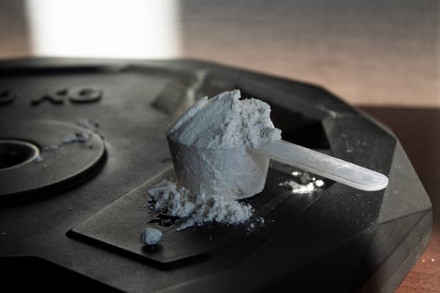 Um scoop de BCAA sobre uma anilha de peso de academia.