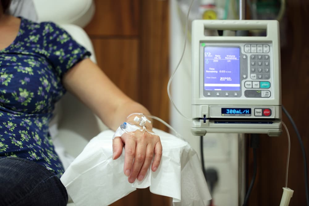 Paciente sentado em uma poltrona durante uma sessão de quimioterapia em um ambiente hospitalar.