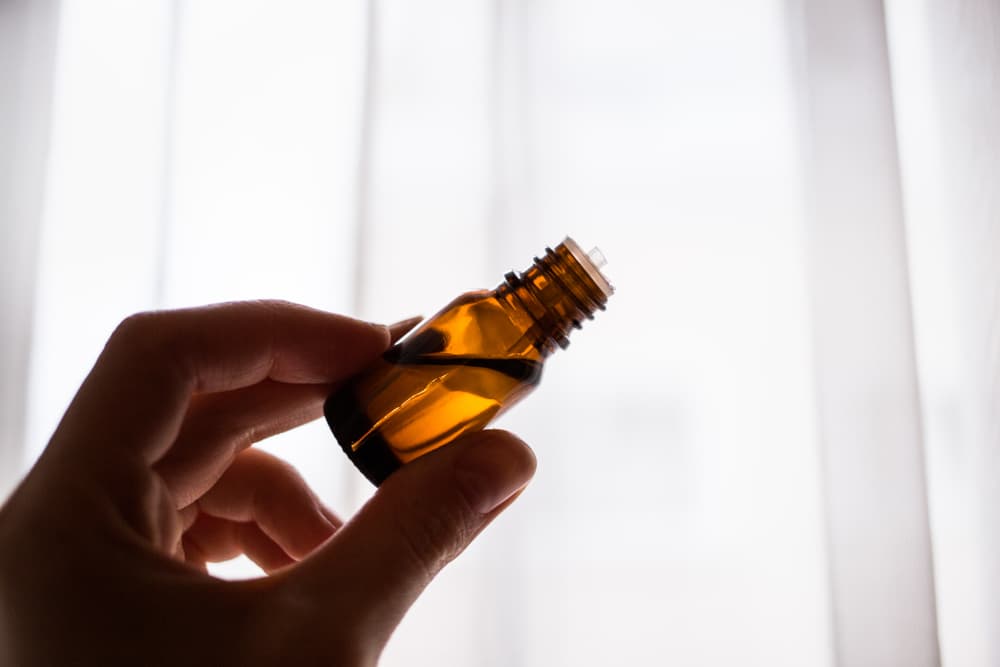 Pessoa com um frasco de medicamento em uma das mãos em ambiente hospitalar.