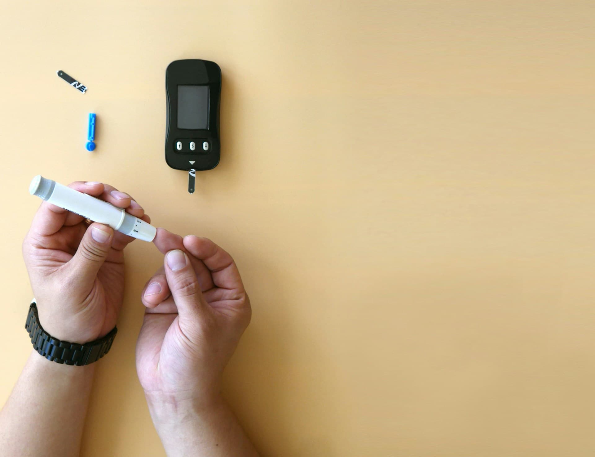Pessoa fazendo o auto teste de diabetes. Furando o dedo e colhendo sangue.