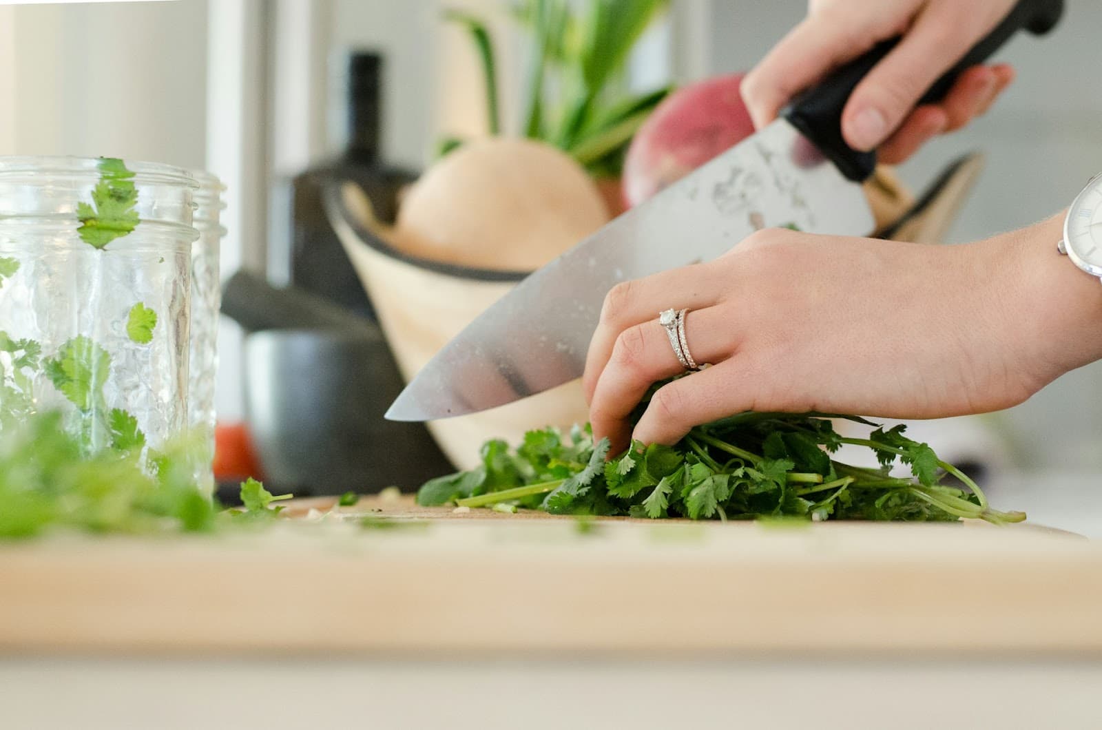 Pessoa preparando alimentos em uma tábua com uma faca.