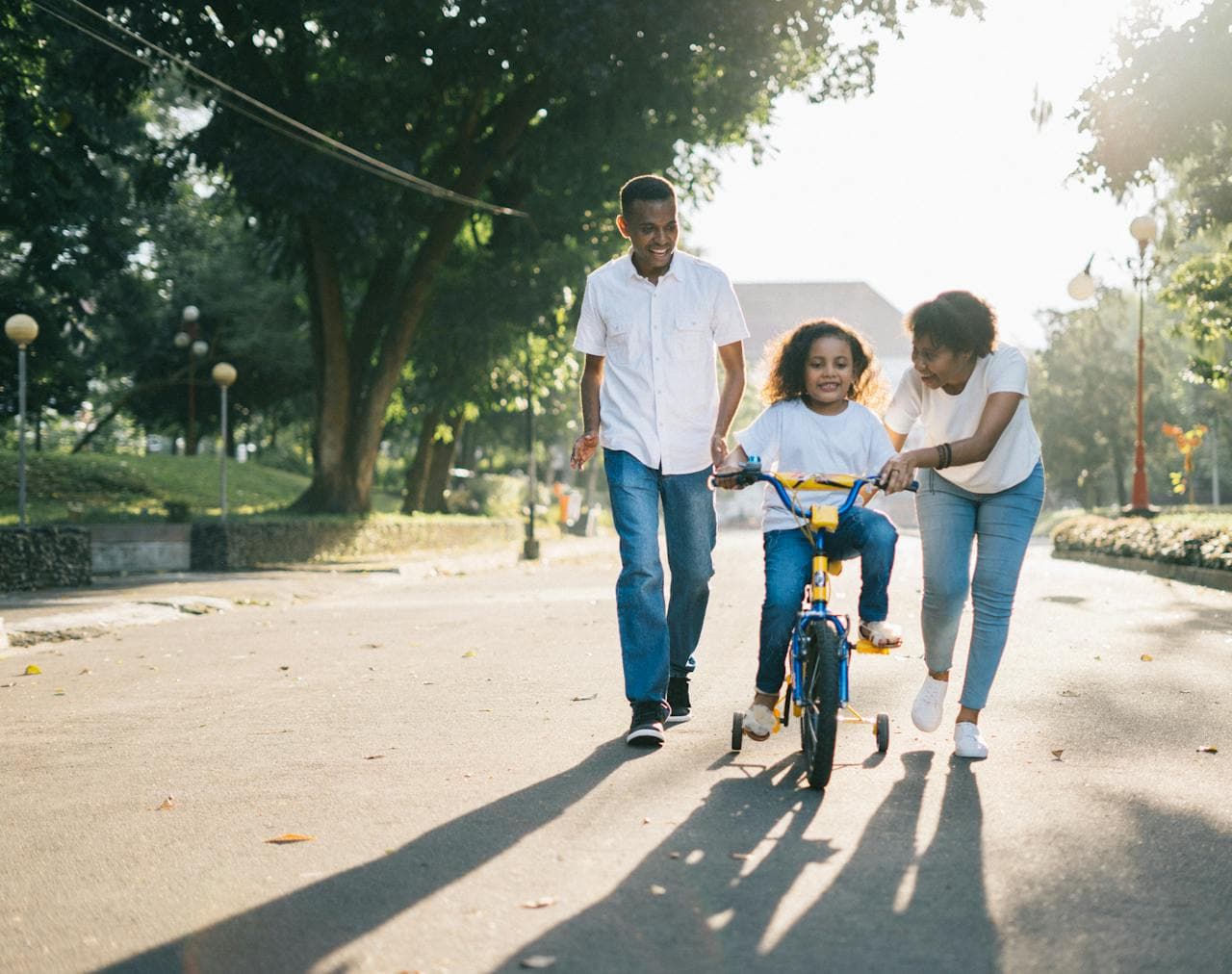 Família composta por dois adultos e uma criança em momento de descontração em um parque arborizado