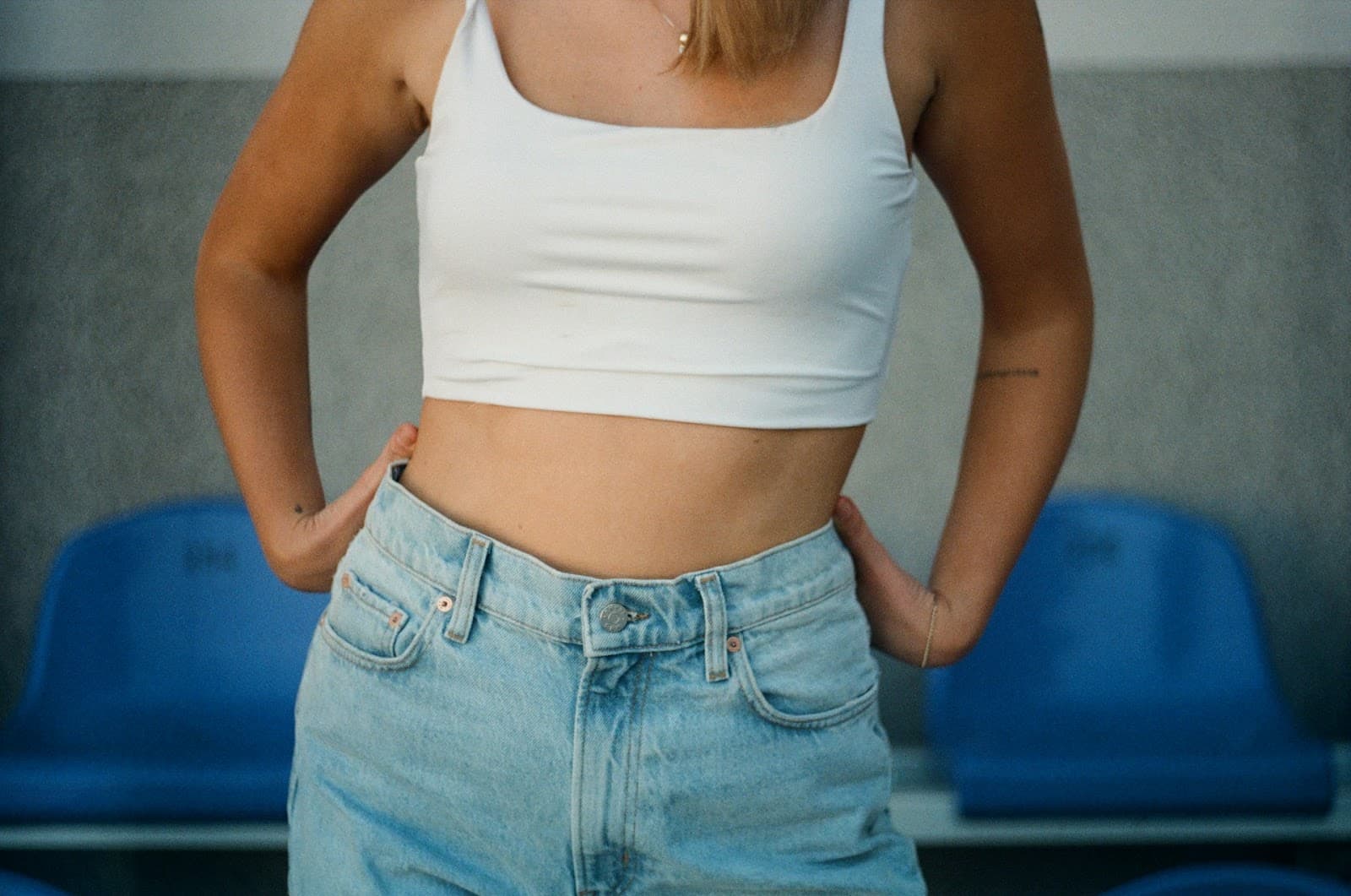 Pessoa de corpo magro vestida com uma calça jeans e uma regata branca