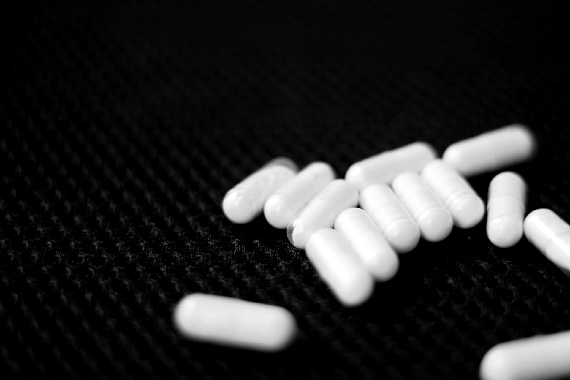 Cápsulas de medicamento antidepressivo espalhadas em uma superfície escura.