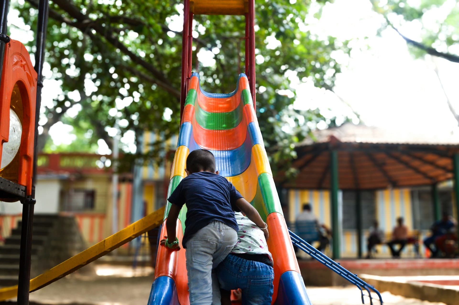 Duas crianças brincando em um escorregador em uma área de recreação infantil.