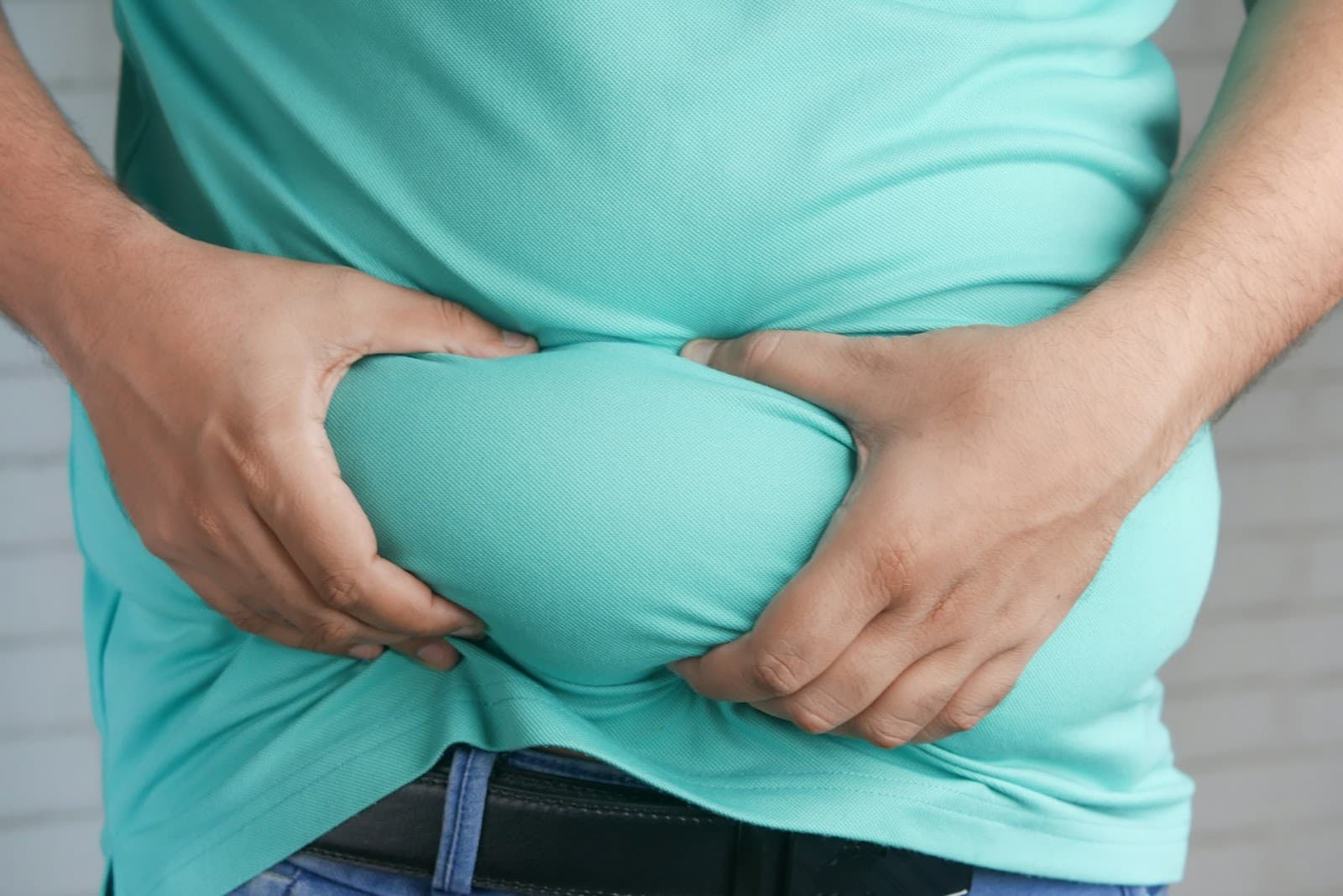 Pessoa excesso de peso segurando a barriga exibindo gordura localizada