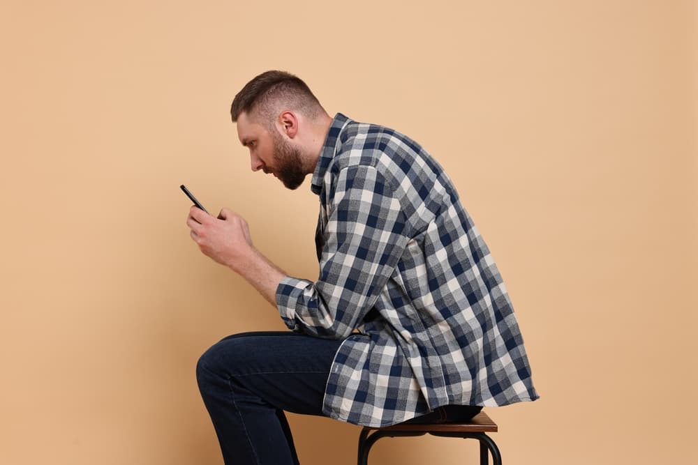 Man,With,Poor,Posture,Sitting,On,Chair,And,Using,Smartphone