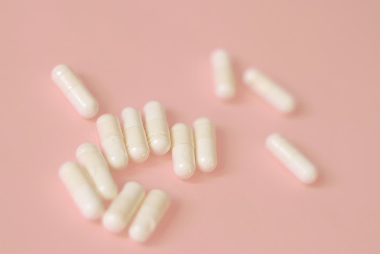Cápsulas de medicamentos sobre uma superfície com tom salmão