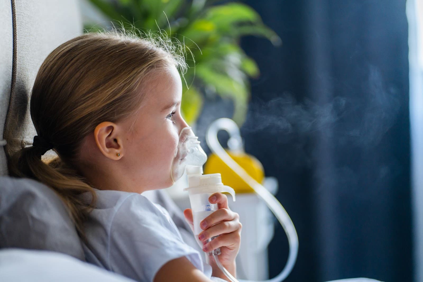 Momento de cuidado: uma menina usando um nebulizador para aliviar a respiração.
