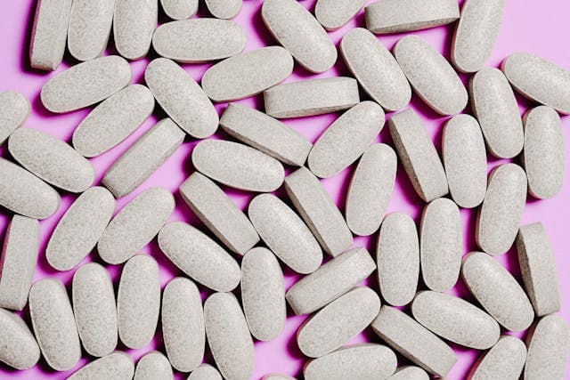 Imagem de medicamentos sobre uma mesa rosa.